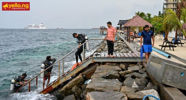 A tourist, along with guides, returns after an open-water diving session near Rasfannu Beach in Malé